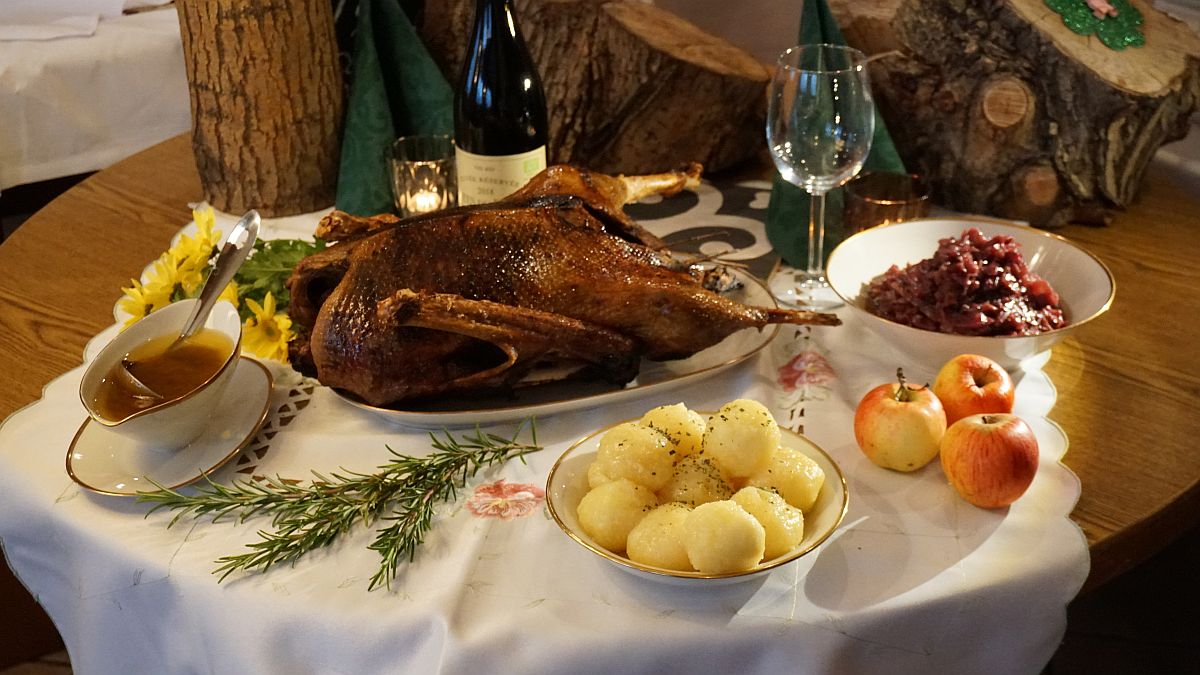 gedeckter Tisch mit Ente, Klößen, Rotkraut, Sauce, Äpfel und Wein