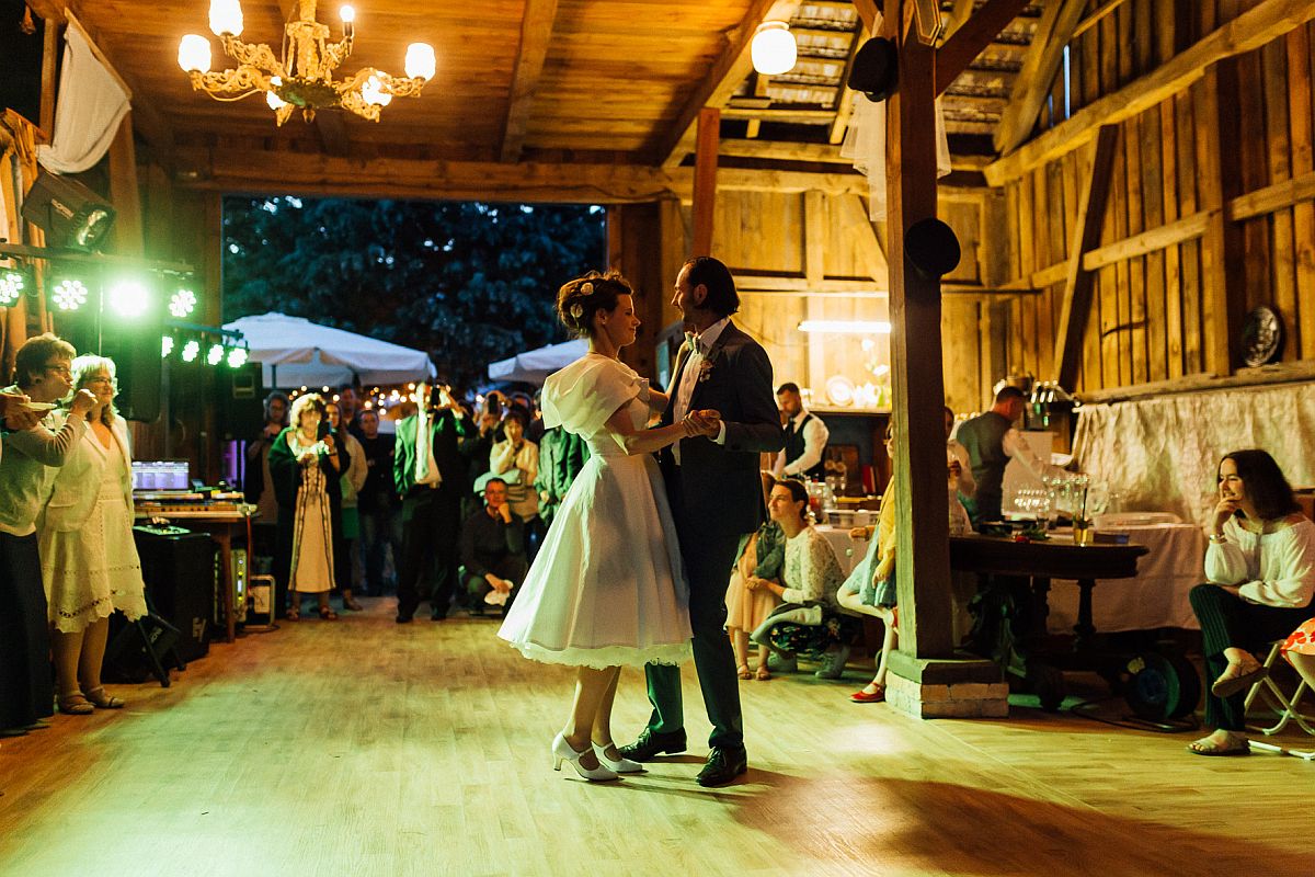 Scheunenhochzeit: Paar tanzt in Scheune, im Hintergrund Gäste